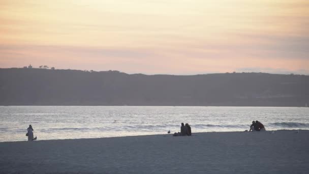 日没時にビーチに座って — ストック動画
