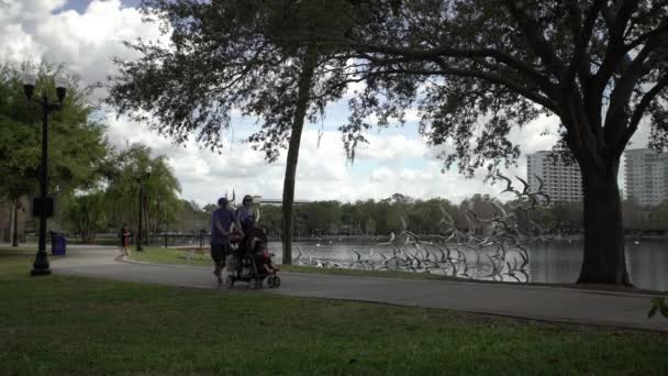 公園の路地を歩く赤ん坊のベビーカーを持つ両親 — ストック動画