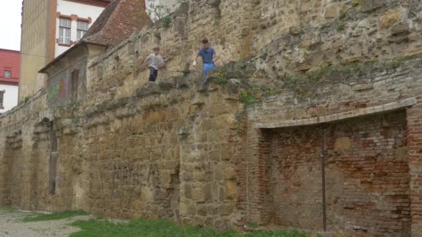 石の壁から飛び降りる二人の若者 — ストック動画