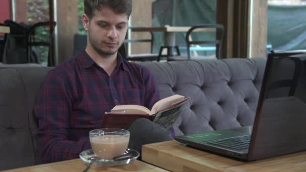 Een Jongeman Die Een Boek Leest Een Koffiehuis — Stockvideo