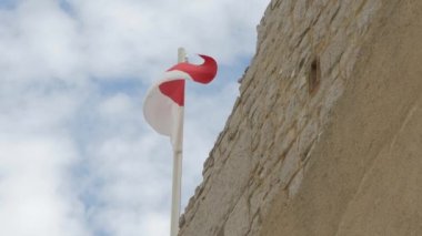 Taştan bir duvarda dalgalanan Monako bayrağı