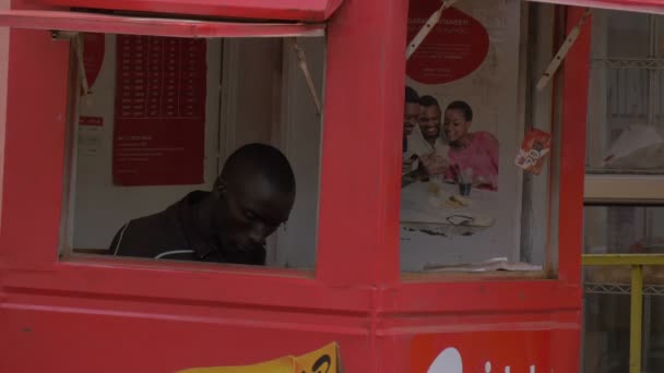 Hombre Africano Sentado Una Cabina Roja — Vídeos de Stock