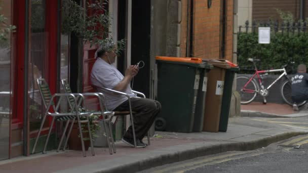 一个男人坐在街上的椅子上 — 图库视频影像