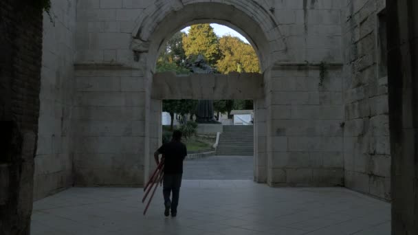Mann Trägt Staffelei Durch Ein Tor — Stockvideo