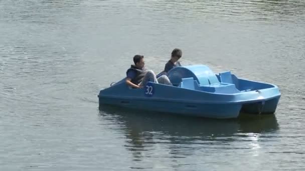 两个男孩在湖上骑着一艘蓝色的船 — 图库视频影像