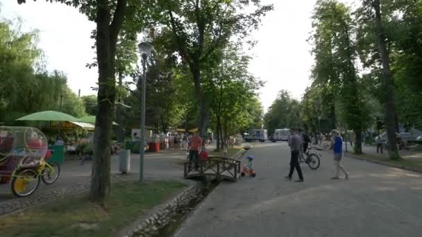 Lidé chodí a jezdí na kole v parku