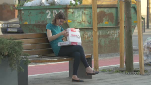 女人坐在那里 腿上夹着一个盒子 — 图库视频影像