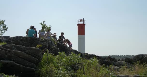 Des Gens Assis Sur Des Rochers Près Phare — Video