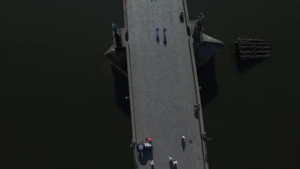 Série lidí kráčejících po Karlově mostě