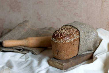 Tahtadaki tahıllı taze ekmek Tekstil ve oklavanın üzerinde