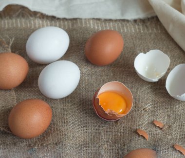 Çuval bezi kahverengi ve beyaz yumurtalar ve içinde yumurta sarısı olan kırık bir yumurta içerir.