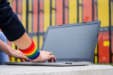 Modern parktaki dizüstü bilgisayarlı ve LGBT bilezik takan kadınların yakın çekimi. LGBTQIA kültürü.