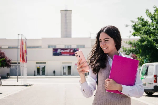 女学生看着校园路上的智能手机 粉红色和蓝色套装 — 图库照片