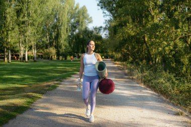 Parktaki yoga sınıfına yürüyen bir kadın.