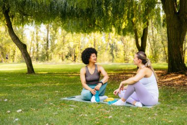 Kadın arkadaşlar parkta spor yaptıktan sonra dinleniyorlar.