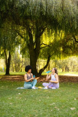 Kadın arkadaşlar parkta egzersiz yaparken dinleniyorlar.