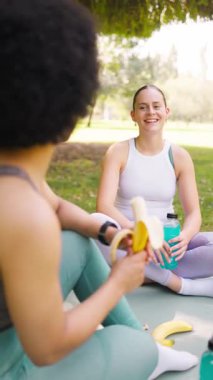 Kadın arkadaşlar parkta antrenmandan sonra dinleniyor ve gülüyorlar.