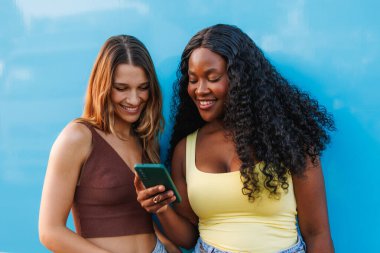 Çeşitli kadın arkadaşlar telefon sosyal medya kullanarak gülümsüyor