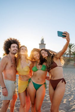 Çeşitli gen z arkadaş grubu gülümseyen ve hafızayı akıllı telefon ile birlikte yakalayan