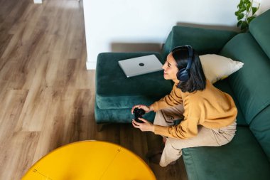 Kulaklık takan, video oyunu oynayan, boş vakitlerin tadını çıkaran bir kadın.