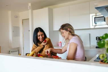 İki kadın birlikte güzel bir mutfakta sağlıklı bir kahvaltı hazırlıyor.