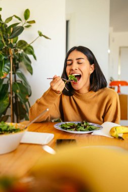 Dengeli bir öğle yemeği için sağlıklı bir salata yerken gözlerini kapatan bir kadın.