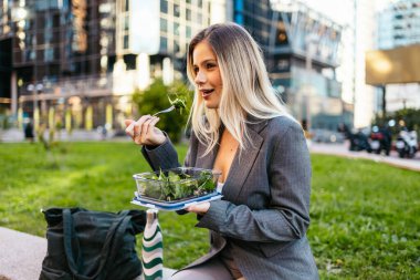 İş kadını şehirde sağlıklı salatanın tadını çıkarıyor.