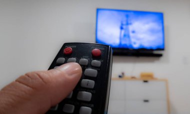 hand with tv remote control points to tv screen