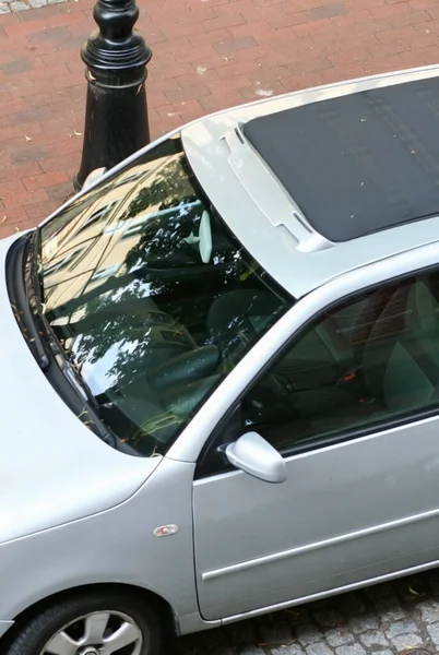 a silver car with a panoramic roof on an old paving stone