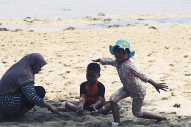 Kasuari Burnu, Sorong, Batı Papua, Endonezya, 22 Ağustos 2021. Bir anne plajda oynayan çocuğuna eşlik eder..