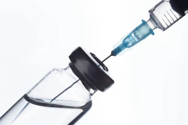 Strzykawka pobiera szczepionkę z butelki medycznej. Na białym. — Zdjęcie stockowe