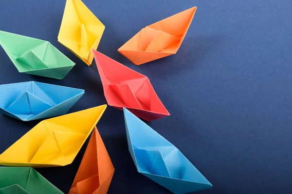 Un grupo de barcos de papel de colores en azul profundo. Concepto de trabajo en equipo, liderazgo. — Foto de Stock