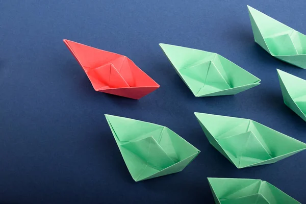 Un grupo de barcos de papel de colores en azul profundo. Concepto de trabajo en equipo, liderazgo. — Foto de Stock