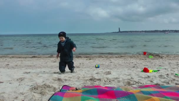 Мальчик бросает камни в море — стоковое видео