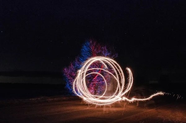 Işık ve ateş olan bir ağacın fotoğrafı, uzun pozlama.
