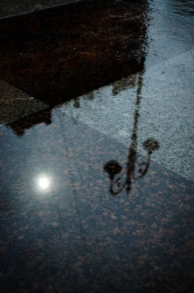 Fener ve bina su birikintisine yansıyor.