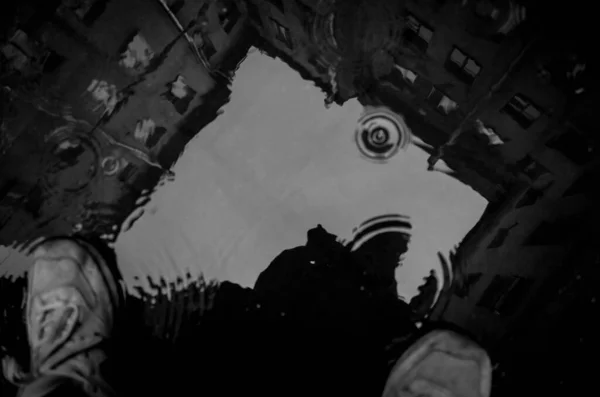 Su birikintisine yansıyan eski bir fotoğrafçı evi ve silueti.