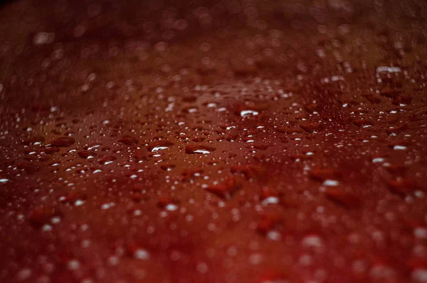 Arabanın kırmızı kaputuna yağmur damlaları düşer.