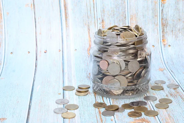 Coins in a jar or glass jar on a wooden background