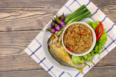 Tahta masadaki beyaz tabakta Tayland uskumrusu acı biber ezmesi.