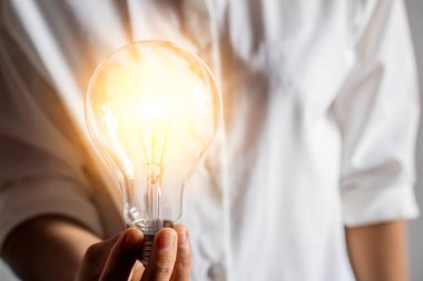 Genç bir kadının elinde ampulle yenilikçi ve ilham verici kavramsal fikirler ve yaratıcılık.