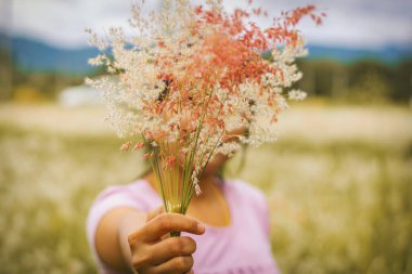 Orta yaşlı kadınların, otların ve dağların ellerinde çimen çiçekleri