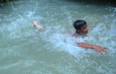 Boru hattında sızıntı var. Ondan sonra çocuklar kavurucu sıcak yaz mevsiminde yüzme havuzu gibi eğlendiler. Gurgaon, Haryana, Hindistan. 08-06-2021.