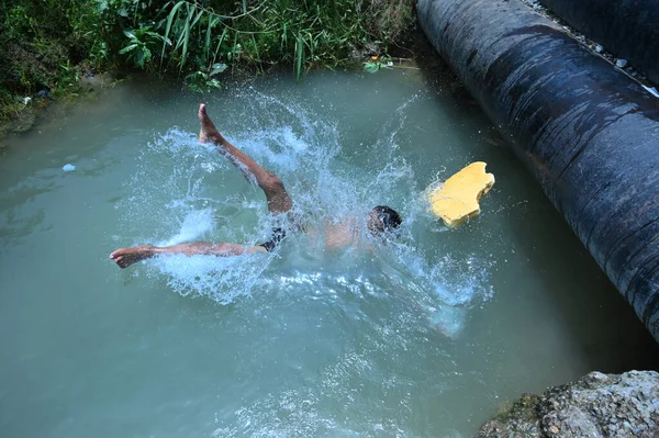 Boru hattında sızıntı var. Ondan sonra çocuklar kavurucu sıcak yaz mevsiminde yüzme havuzu gibi eğlendiler. Gurgaon, Haryana, Hindistan. 08-06-2021.