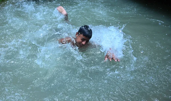 Boru hattında sızıntı var. Ondan sonra çocuklar kavurucu sıcak yaz mevsiminde yüzme havuzu gibi eğlendiler. Gurgaon, Haryana, Hindistan. 08-06-2021.