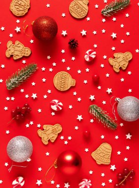 Kırmızı arka planda Noel süsleri ve zencefilli kurabiyeler. Yeni