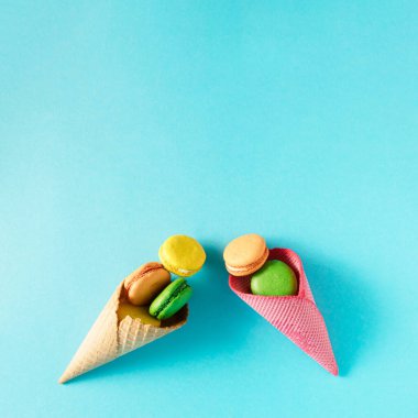 Renkli badem kurabiyeleri. Cyan arkaplan üzerinde canlı düz uzanır.