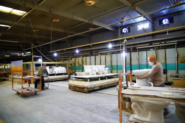 İşçiler üretim atölyesindeki seramik banyo üretim hattını inceliyorlar..