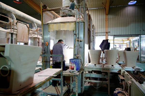 İşçiler üretim atölyesindeki seramik banyo üretim hattını inceliyorlar..