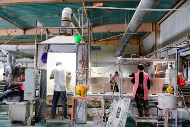 İşçiler üretim atölyesindeki seramik banyo üretim hattını inceliyorlar..